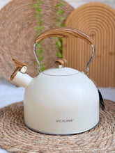 Load image into Gallery viewer, White kettle with wooden handle and spout on a woven mat