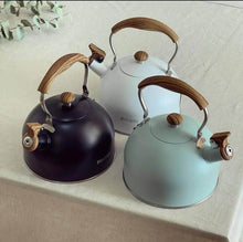 Load image into Gallery viewer, Three kettles with wooden handles on a light surface.