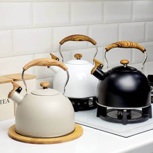 Load image into Gallery viewer, Set of three kettles with wooden handles on a kitchen counter.