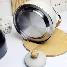 Load image into Gallery viewer, White ceramic pot with metal lid on a wooden trivet, surrounded by kitchen items.