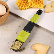 Load image into Gallery viewer, An image showing a black and green adjustable measuring spoon with levels marked in green, placed on a kitchen counter with ingredients around it.