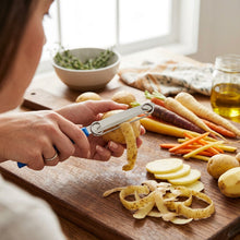 تحميل الصورة في عارض المعرض، 3-in-1 Multifunctional Vegetable Knife & Peeler | Adjustable Spring Slicer & Shredder on a wooden cutting board.