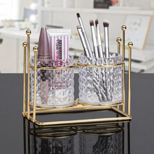 تحميل الصورة في عارض المعرض، Gold-framed glass holder with makeup items on a reflective surface