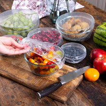 Load image into Gallery viewer, Person using plastic food storage covers on bowls of fresh fruits and vegetables, showcasing easy food preservation.