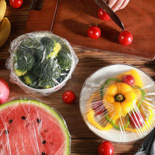 Load image into Gallery viewer, Plastic food storage covers wrapping fresh fruits and vegetables on a wooden table.