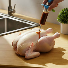 Load image into Gallery viewer, Person injecting a chicken with a syringe on a kitchen counter.