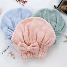 Load image into Gallery viewer, Three colorful hair turban hats on a white surface with a magazine underneath.