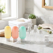Load image into Gallery viewer, A set of clear plastic travel-sized toiletry bottles and containers with white caps, including two translucent squeeze bottles in yellow and pink, one in mint green, one pump bottle, one spray bottle, one small bottle, and a small round jar, arranged on a light gray background.