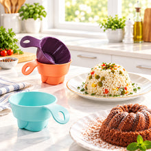 تحميل الصورة في عارض المعرض، Colorful silicone measuring cups on a kitchen counter with a plate of food in the background.