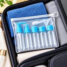 Load image into Gallery viewer, A clear plastic zippered travel toiletry pouch containing five small empty bottles with light blue caps and a funnel, shown inside an open suitcase with folded towels.