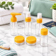Load image into Gallery viewer, Five small clear plastic travel-sized bottles with mint green caps and accessories, including a pump bottle, two spray bottles, a small jar with a lid, and a small clear plastic spoon, arranged on a light wood grain surface.