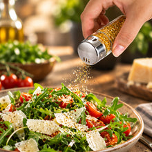 تحميل الصورة في عارض المعرض، Hand sprinkling seasoning from a pepper grinder onto a salad.