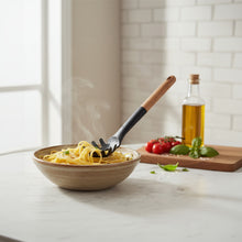 تحميل الصورة في عارض المعرض، Bowl of pasta with a wooden fork, tomatoes, and basil on a kitchen counter.