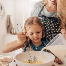 Load image into Gallery viewer, Woman and child in a kitchen, with the child stirring a bowl and the woman pouring ingredients.