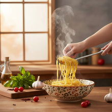 تحميل الصورة في عارض المعرض، A stainless steel pasta server with a long handle, resting on a dark surface with vegetables in the background.