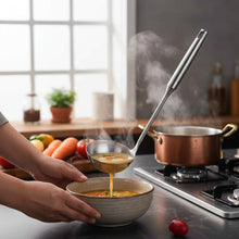 تحميل الصورة في عارض المعرض، A stainless steel soup ladle with a long handle, displayed on a dark surface with vegetables in the background.