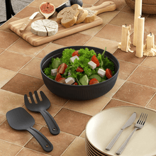 Load image into Gallery viewer, Black salad bowl with a salad on a tiled table, surrounded by utensils and bread.