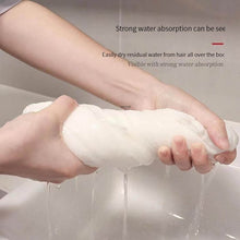 Load image into Gallery viewer, White fluffy substance being squeezed by hands with text about water absorption.