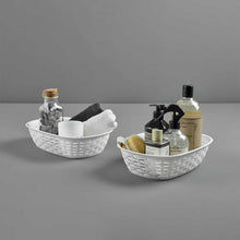 Load image into Gallery viewer, Two white oval storage baskets containing toiletries, towels, and decorative bottles on a grey background.