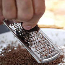Load image into Gallery viewer, Person grating chocolate with a stainless steel cheese grater on a white plate filled with chocolate shavings.