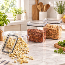 تحميل الصورة في عارض المعرض، Clear glass containers with lids on a brown surface, filled with popcorn and beans.