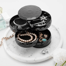 Load image into Gallery viewer, A black, diamond-shaped, multi-tiered jewelry and accessories box with various items such as bracelets, rings, and a necklace displayed on a marble surface.
