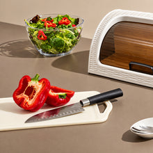 تحميل الصورة في عارض المعرض، Red bell pepper cut in half on a cutting board with a knife, next to a bowl of salad on a neutral background.