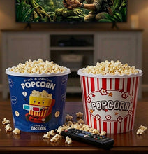 تحميل الصورة في عارض المعرض، Two popcorn buckets on a wooden table in a living room setting, with a TV in the background showing a jungle scene. One bucket is blue with a cartoon character and the text 'Fresh &amp; Delicious POPCORN BREAK', and the other is red and white striped with 'POPCORN' written on it.
