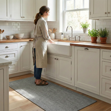 تحميل الصورة في عارض المعرض، Woman in a kitchen wearing an apron, standing by a sink.
