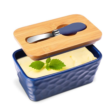 Blue porcelain butter dish with bamboo lid, spreader, and fresh herbs, perfect for storing butter.