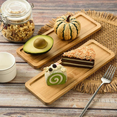 Wooden trays with various food items including a cake, avocado, and small pumpkin on a wooden surface.