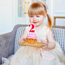 Load image into Gallery viewer, Child holding a small cake with a lit candle on a couch
