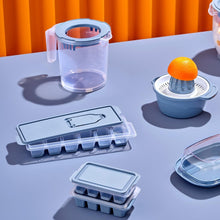 Load image into Gallery viewer, Set of kitchen items including a pitcher, juicer, and ice cube trays on a table with an orange curtain background.
