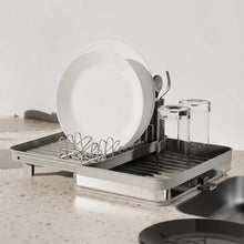 تحميل الصورة في عارض المعرض، Dish drying rack with plates, glasses, and cutlery on a kitchen counter.
