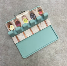 Load image into Gallery viewer, Teal silicone mat with ice cube tray on a wooden board packaging

