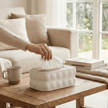Load image into Gallery viewer, Person reaching for tissues from a white tissue box on a wooden table in a cozy living room.
