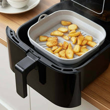 تحميل الصورة في عارض المعرض، Black air fryer with a basket containing fried potatoes on a wooden countertop.
