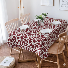 Load image into Gallery viewer, Dining table with a red and white patterned tablecloth, surrounded by wooden chairs.
