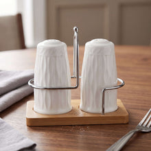تحميل الصورة في عارض المعرض، 2-Piece Porcelain Spice Shaker Set - Seasoning Jars with Wooden Base &amp; Metal Handle on a wooden table.
