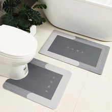Load image into Gallery viewer, Two gray bath mats with &#39;HOME&#39; text on a bathroom floor.

