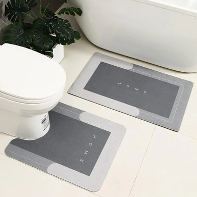 Two gray bath mats with 'HOME' text on a bathroom floor.