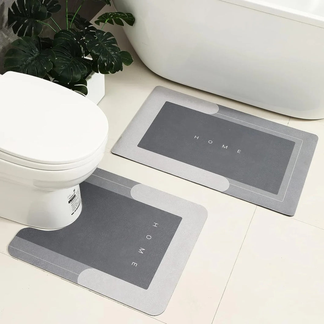 Two gray bath mats with 'HOME' text on a bathroom floor.
