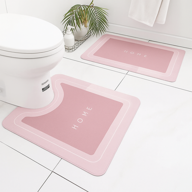 Pink bath mats with 'HOME' text on a bathroom floor.