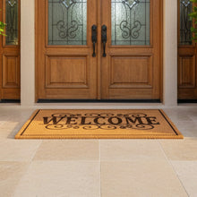 تحميل الصورة في عارض المعرض، Wooden front door with decorative glass panels and a 'Welcome' mat on a stone patio.
