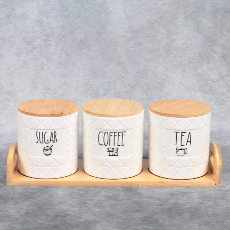 Three ceramic canisters labeled 'Sugar', 'Coffee', and 'Tea' with wooden lids on a gray background.