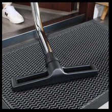 Load image into Gallery viewer, Black broom on a textured mat with a white shoe in the background

