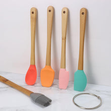 تحميل الصورة في عارض المعرض، Set of four colorful spatulas with wooden handles on a marble surface.

