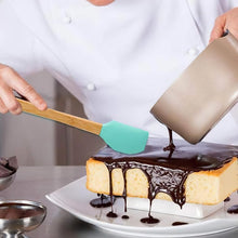 تحميل الصورة في عارض المعرض، Person drizzling chocolate sauce over a cake with a spatula
