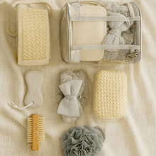 Load image into Gallery viewer, Set of bath products including a brush, loofah, and soap on a beige fabric background
