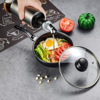 Pouring oil from a stainless steel dispenser into a bowl of noodles topped with fresh vegetables and an egg.